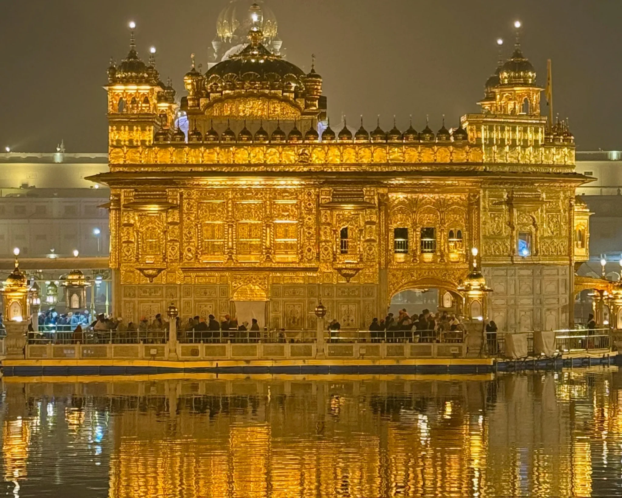 Golden Temple at night reflecting on calm water, serene spiritual scene.