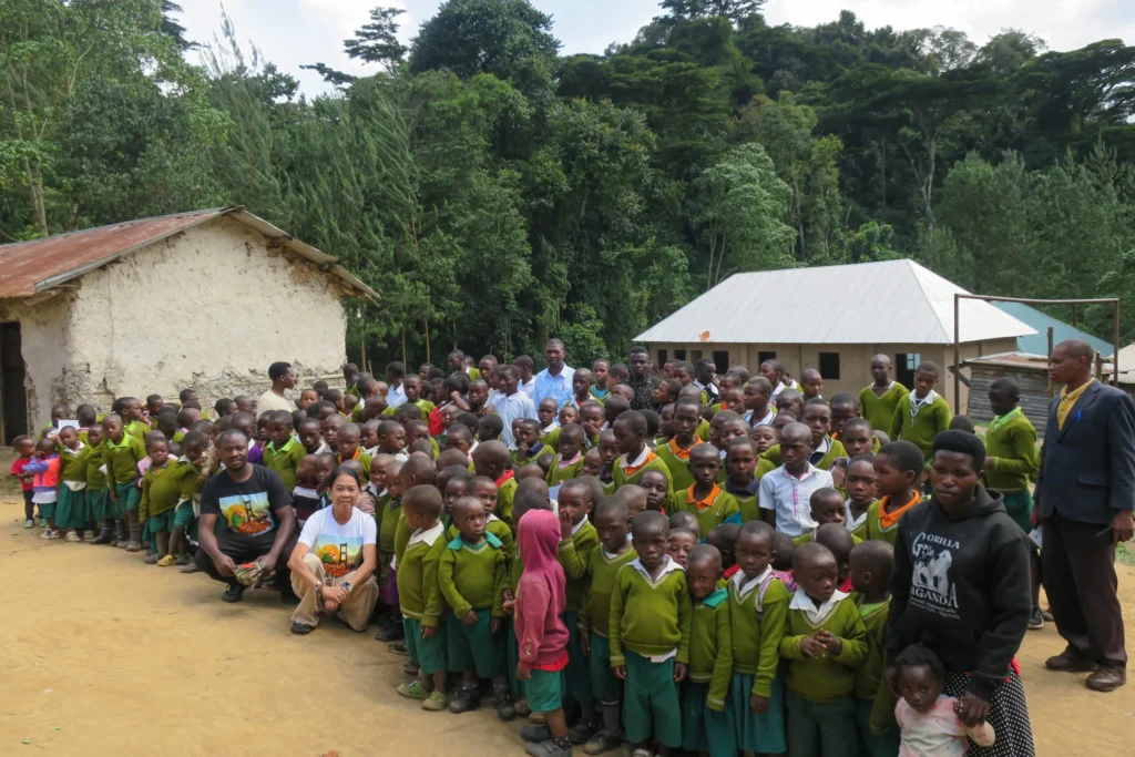 Smiling children in green uniforms outdoors near rustic buildings.