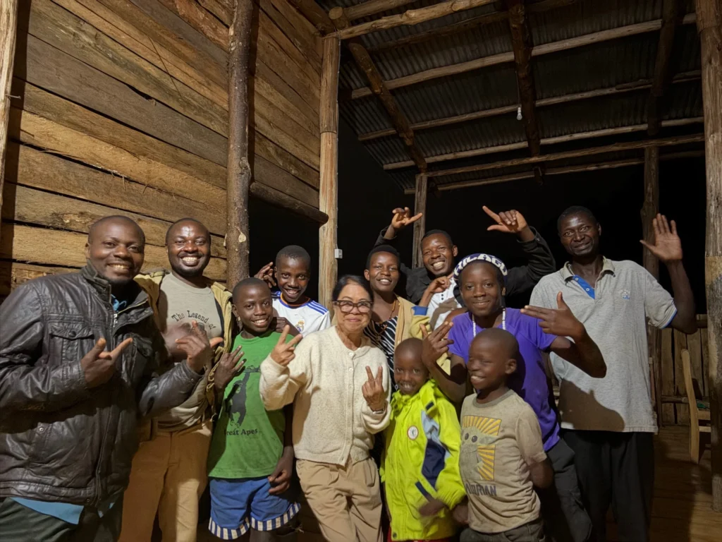 Happy adults and children smiling on a wooden porch at night, making peace signs.