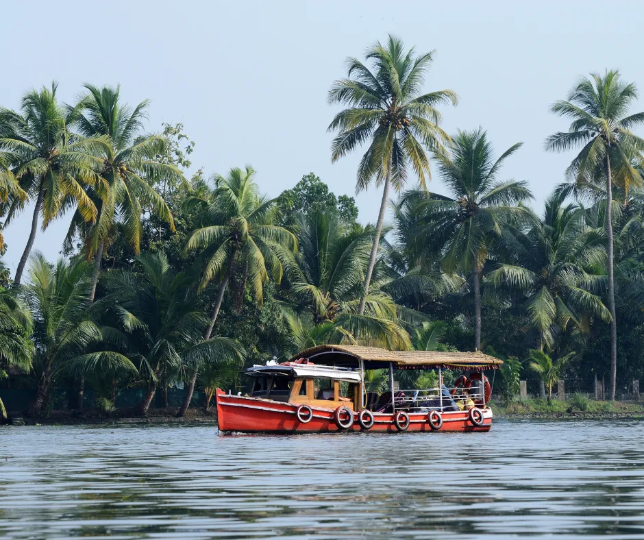 Red boat on calm tropical water surrounded by green palm trees