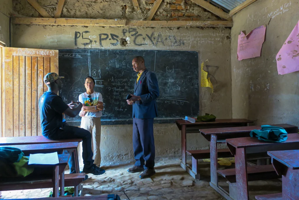 Rustic classroom with wooden desks, chalkboard, and collaborative discussion among people.