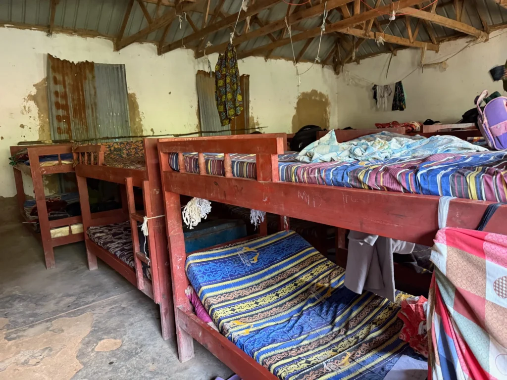 Rustic bunk beds with colorful mismatched bedding in a simple, worn room.