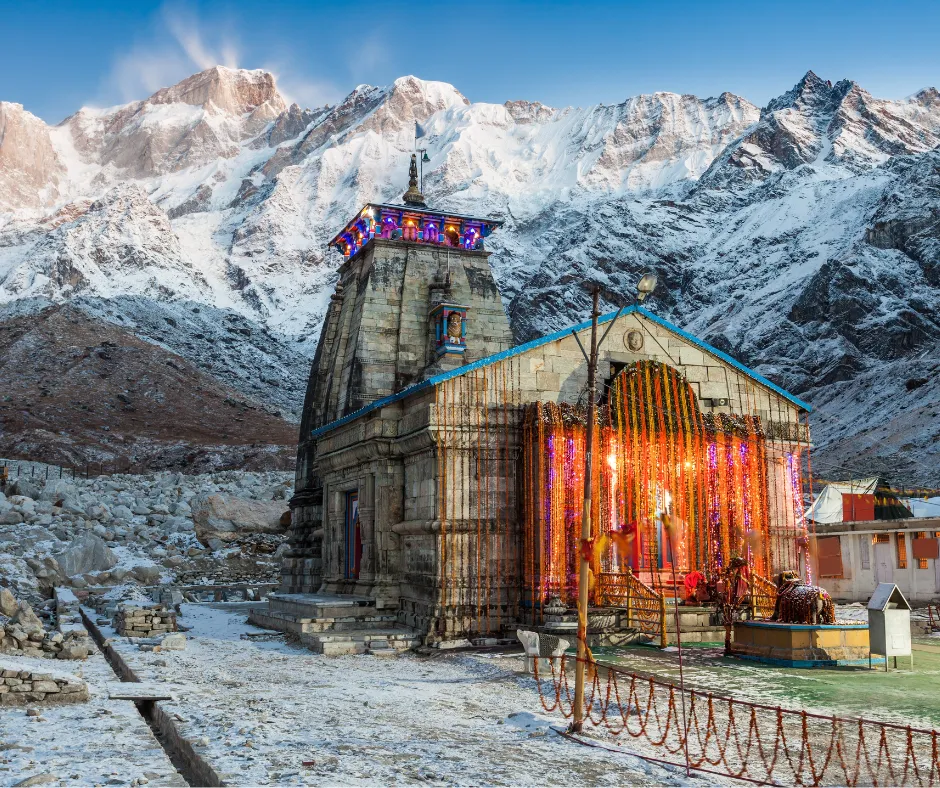 Stone temple illuminated in snowy mountains under clear sky, serene and majestic.