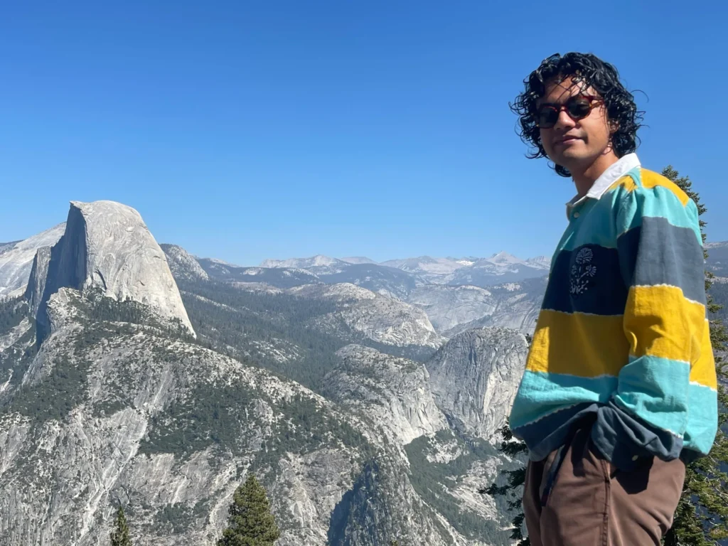 Smiling person in striped sweater at Yosemite Half Dome viewpoint.