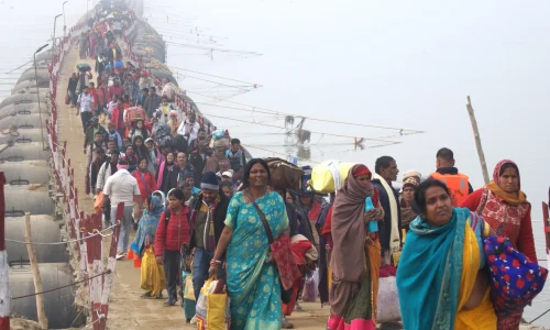 Crowd in colorful clothes crossing narrow foggy bridge, depicting journey and community.